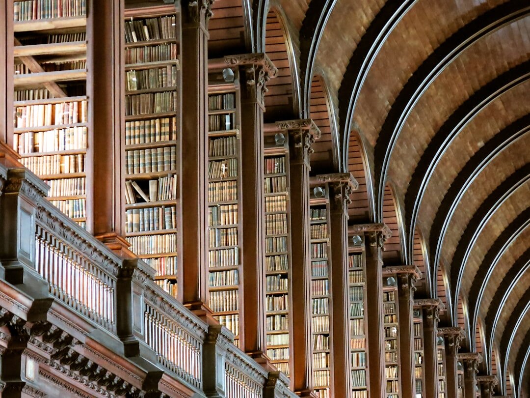 Old library with tall wooden shelves full of books in warm light